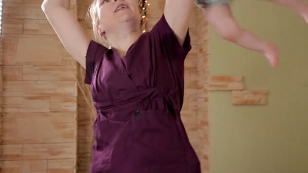 Женщина-педиатр, массажист, показывающая упражнения в физическом воспитании ребенка. Ребенок, здоровье — стоковое видео