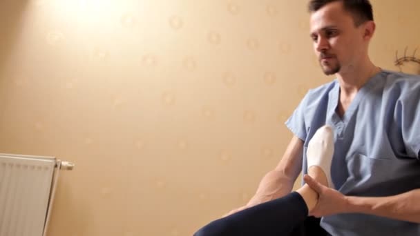 Mannelijke fysiotherapeut masseer het been van een patiënt in de fysiotherapeutische ruimte. Behandeling, Massage, revalidatie, ziekte — Stockvideo