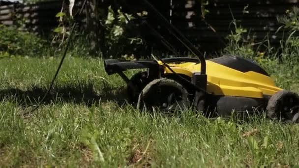 Dziewczyna jest koszenie nierówny trawnik z żółtym kosiarki boso. zbliżenie — Wideo stockowe