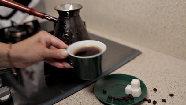 Primer plano de una taza de café, granos de café tostados, sobre la mesa junto a la estufa. café de la mañana — Vídeos de Stock