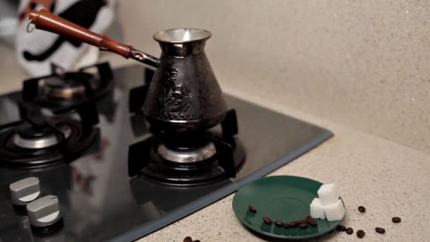 Primer plano de una taza de café, granos de café tostados, sobre la mesa junto a la estufa. café de la mañana — Vídeo de stock