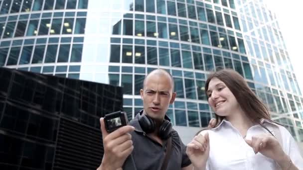 Туристи беруть селфі-танці на екшн-камеру в центрі міста на тлі хмарочосів — стокове відео