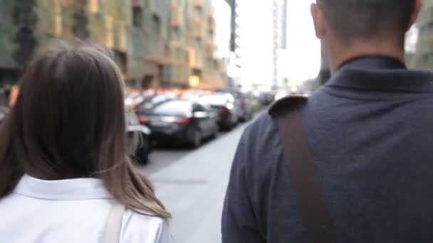 Arkadaşlar, bir adam ve bir kadın, şehir merkezinde yoğun bir sokakta yürüyüş ve konuşan, gülümseyen. arka görünüm — Stok video