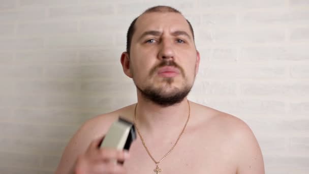 Egy ember leborotválja a nagy szakálla egy elektromos borotva. közeli portré egy személy — Stock videók