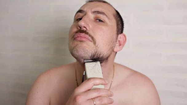 Egy ember leborotválja a nagy szakálla egy elektromos borotva. közeli portré egy személy — Stock videók