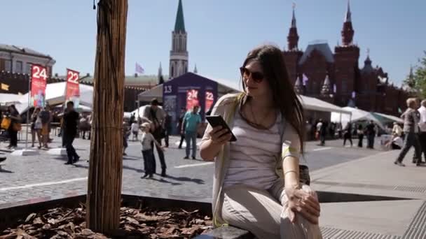 A woman using a smartphone speaks on Red Square in Moscow, in front of the Kremlin — Stock Video