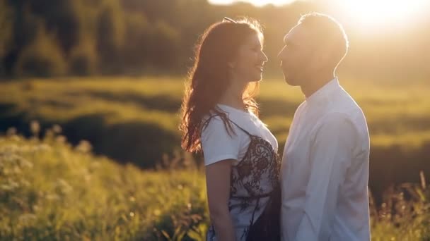 Giovane uomo e donna passeggiano in un prato al tramonto in estate. Romanticismo. Amore estivo insieme gioia ricordi romantici per sempre insieme concetto — Video Stock