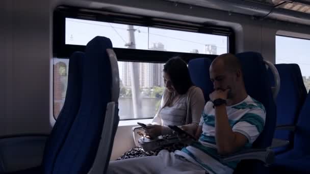 Frau und Mann, die mit dem Zug unterwegs sind, nutzen ihre Smartphones, um Zeit im Internet zu verbringen — Stockvideo