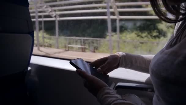 Mooi meisje typen SMS op haar Smartphone zittend op de plek in een forenzentrein in de stad op een zomerdag — Stockvideo