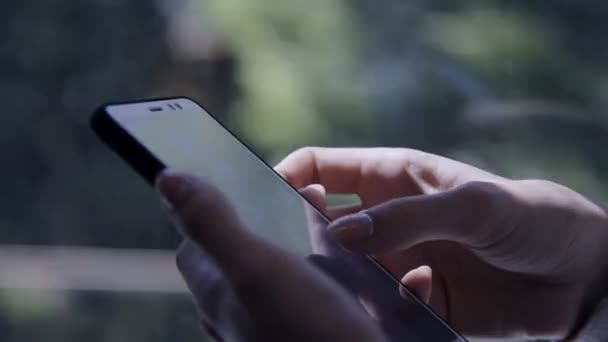 Hermosa chica escribe sms en su teléfono inteligente sentado en el lugar en un tren de cercanías en la ciudad en un día de verano — Vídeo de stock