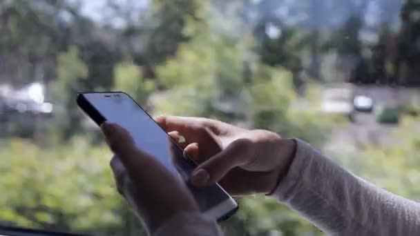 美しい女の子は、夏の日に市内の通勤電車の中でその場に座って彼女のスマートフォン上のSMSをタイプ — ストック動画