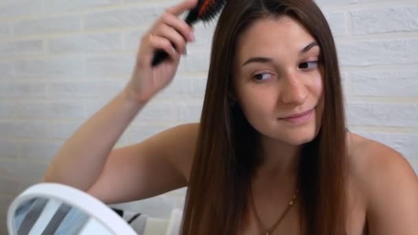 Giovane bella donna pettinarsi i capelli davanti allo specchio — Video Stock