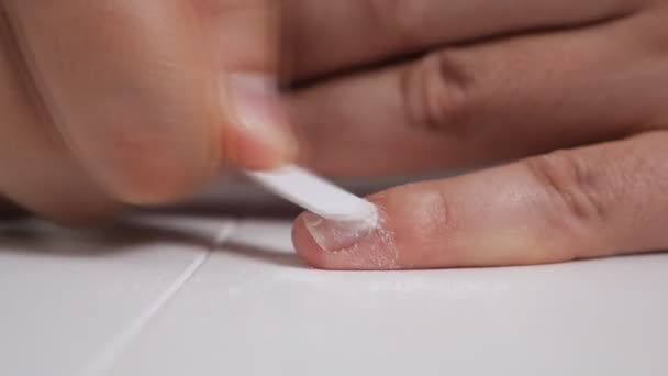 Un chauve s'assoit à une table et s'occupe de ses ongles. Lime à ongles — Video