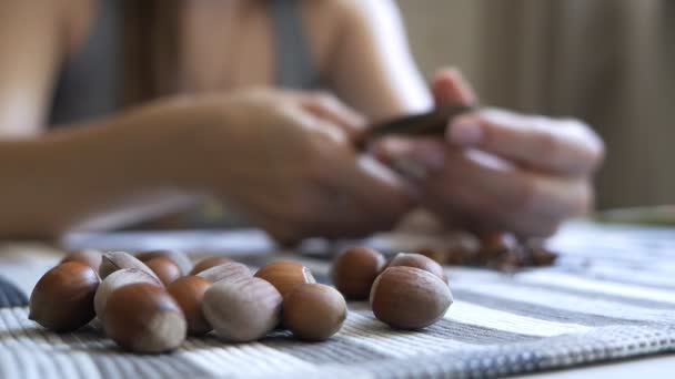 Close-up dari tangan seorang gadis yang duduk di meja dan membersihkan filbert. Tasty, kacang sehat — Stok Video