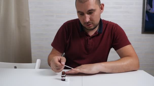 Een respectabele kale man behandelt zijn nagels met een speciaal medicijn om de schimmel te genezen. Hand schimmel behandeling thuis — Stockvideo