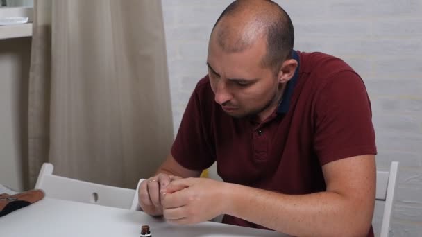 Un hombre calvo respetable trata sus uñas con una droga especial para curar el hongo. Tratamiento de hongos en la mano en casa — Vídeo de stock