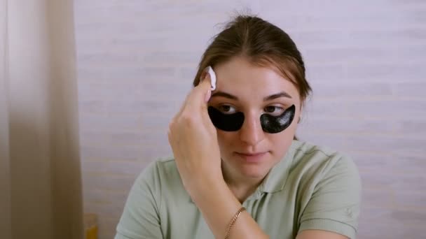 Mooie jonge vrouw doet huidverzorging rond de ogen. Skin Care concept, meisje reinigt haar huid met een wattenstaafje met lotion — Stockvideo