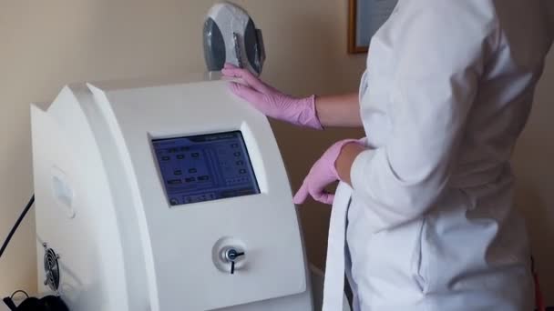 Equipo médico. La mano femenina enciende el dispositivo electrónico para el procedimiento cosmético, cámara lenta — Vídeos de Stock