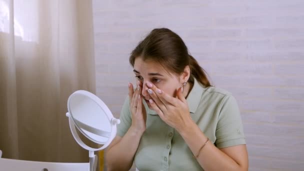 Ung kvinna grimasera hennes ansikte och titta i spegeln i rummet — Stockvideo