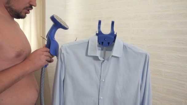 Un uomo accarezza, vapore, bollire una camicia blu a casa — Video Stock