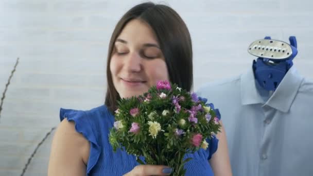 Uma jovem com flores nas mãos. O processo de vapor roupas vapor. Detalhes azuis. Home care e Romântica — Vídeo de Stock