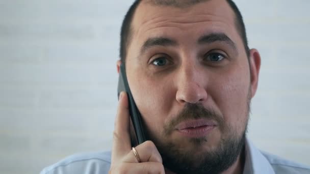 Молодий чоловік одягає сорочку і розмовляє по телефону — стокове відео