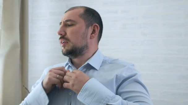 Manos de hombre abotonando una camisa blanca. Un hombre con un apósito de barba usa ropa para trabajar por la mañana. Cabello torácico y masculinidad machista — Vídeos de Stock