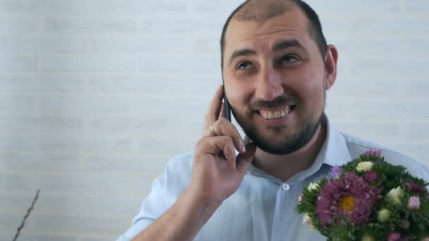 Jonge kerel in een shirt met een helder boeket van bloemen thuis — Stockvideo