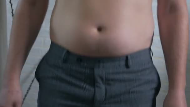 Крупный план, мужской живот, лишний вес. Молодой человек с голым жирным животом трясет жировыми складками на животе, ожирением, здоровьем, пивным животом — стоковое видео