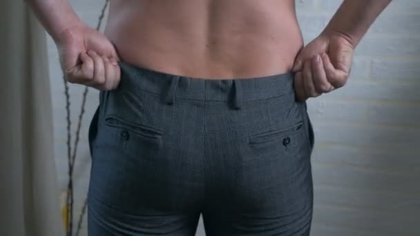 Man puts on pants, view from the back — Stock Video