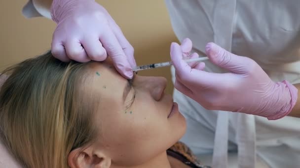 Clínica de Beleza. Mãos de esteticista com luvas que fazem injeções de envelhecimento de cara na pele feminina. Mulher recebe tratamentos faciais cosméticos. Injeções de colagénio botox — Vídeo de Stock