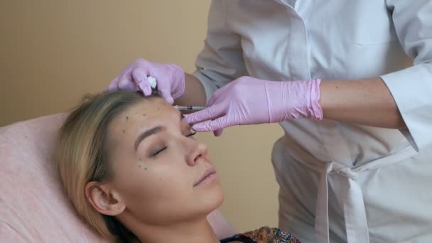 Clínica de belleza. Manos esteticistas con guantes haciendo inyecciones de envejecimiento facial en la piel femenina. La mujer recibe tratamientos faciales cosméticos. Inyecciones de colágeno Botox — Vídeos de Stock