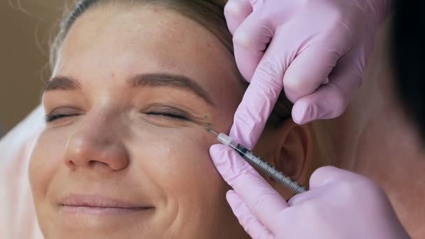 Mujer hermosa recibiendo inyección cosmética en el área de los ojos de esteticista. concepto de belleza limpia — Vídeos de Stock