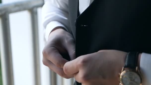 Homem elegante em um terno e camisa branca abotoando um colete colete de pé perto da janela. Fechar — Vídeo de Stock