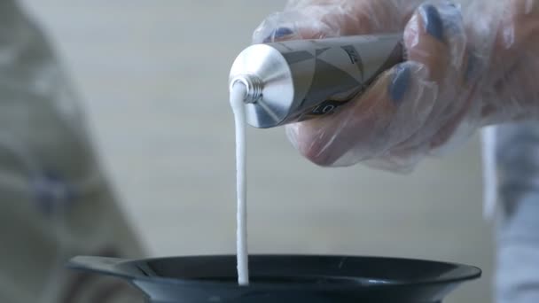 Stylist pressar en tub med hårfärgningsmedel i en skål. Hårvård — Stockvideo