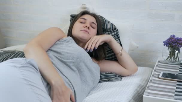 Kobieta w ciąży dotykając dziecko s brzuch i leżąc na łóżku w domu. — Wideo stockowe