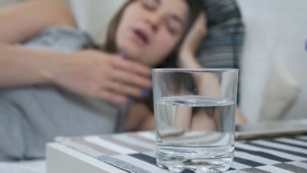 Egy terhes lány alszik a kanapén, felébred, és egy pohár vizet iszik. Fáradt terhes nő vágyik egy pohár vizet — Stock videók