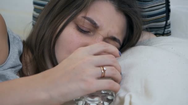 Ένα έγκυος κορίτσι κοιμάται στον καναπέ, ξυπνάει και πίνει ένα ποτήρι νερό. Κουρασμένη έγκυος γυναίκα λαχταρά για ένα ποτήρι νερό — Αρχείο Βίντεο