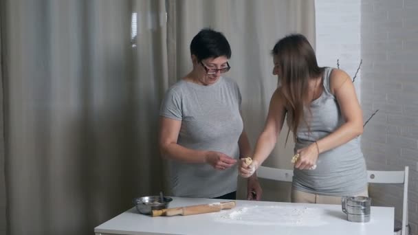 Filha grávida e mãe cozinhar juntos na cozinha, filha ajuda a mãe amassar massa para panquecas ou biscoitos — Vídeo de Stock