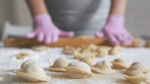 Vrouwen in heldere handschoenen rollen het deeg uit op de tafel. Zelfgemaakte gerechten, ravioli, dumplings — Stockvideo