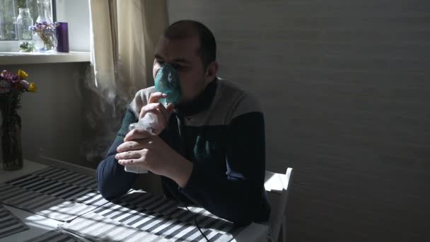 Una persona enferma inhala a través de un inhalador nasal mientras está sentada en un sofá. Cara cerrada. Utilice un nebulizador e inhalador para el tratamiento — Vídeo de stock