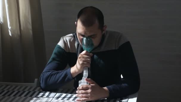 A sick person inhales through a nasal inhaler while sitting on a sofa. Close up face. Use a nebulizer and inhaler for treatment — Stock Video