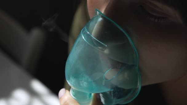 Use nebulizador e inhalador para el tratamiento. Mujer joven inhalando a través de la máscara del inhalador. Vista lateral — Vídeos de Stock