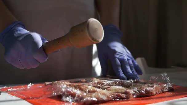 Il cuoco batte la carne su un tagliere. La ragazza batte la carne fresca per le bistecche. Rallentatore — Video Stock