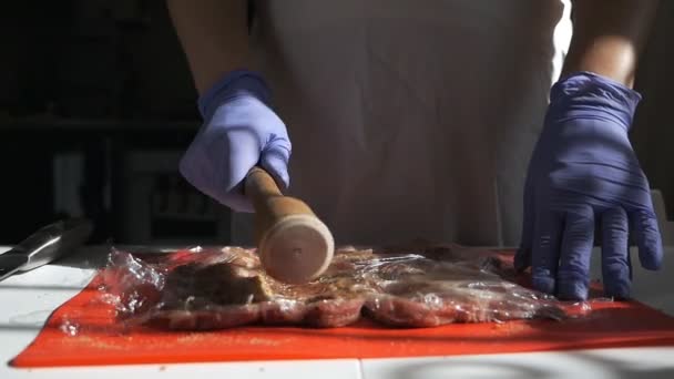 The cook beats meat on a cutting board. Girl beats fresh meat for steaks. — Stockvideo