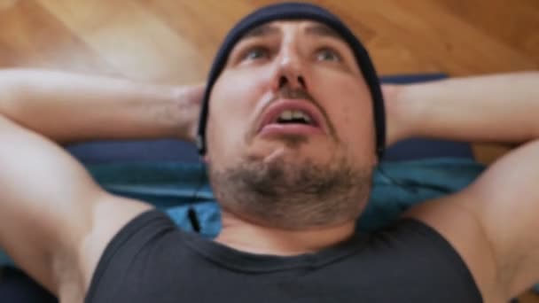 괴상한 남자는 집에서 매트에 누워 동적 복부 위기 운동을하고있다. 스포츠 유머 컨셉 — 비디오
