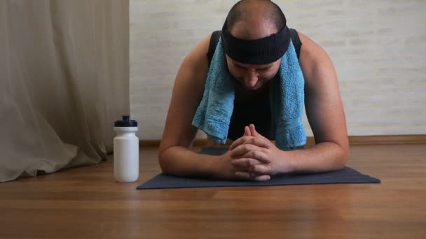 Lustiger dicker Mann auf der Yogamatte müde vom Unterricht, verbraucht Wasser, kühlt sich ab — Stockvideo