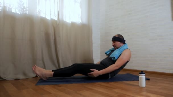 Uomo grasso divertente sta cercando di fare esercizi di yoga su un tappeto sullo sfondo. Yogi maschili brutali — Video Stock