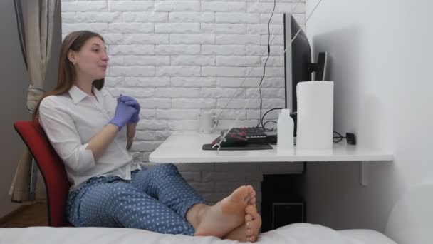 Женщина в хирургических перчатках работает за компьютером. Работа из дома во время концепции пандемии коронавируса — стоковое видео