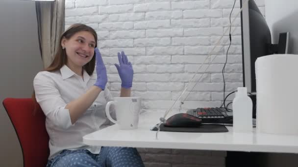 Женщина в хирургических перчатках работает за компьютером. Работа из дома во время концепции пандемии коронавируса — стоковое видео